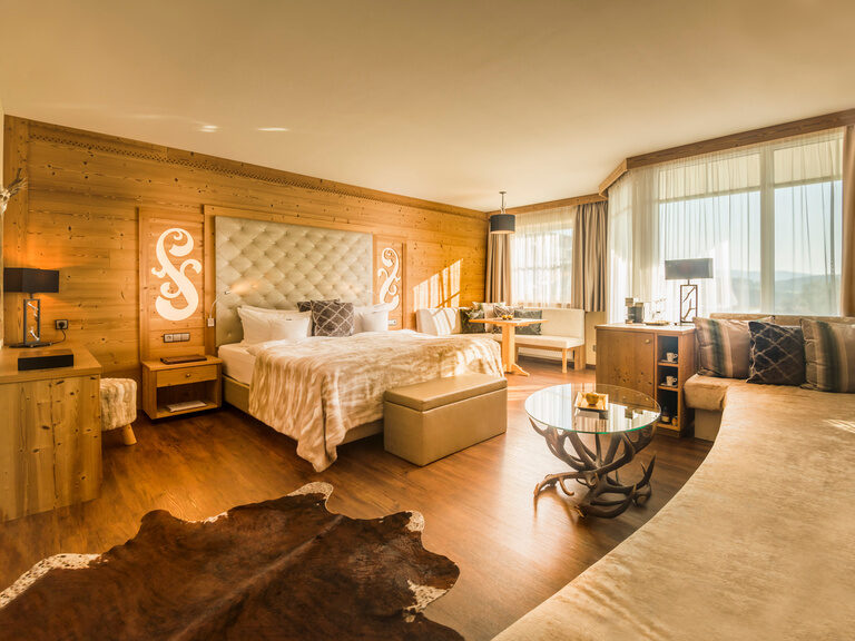 Das einladende Schlafzimmer der Hirschenstein-Suite De Luxe mit moderner Beleuchtung und hochwertigen Möbeln.
